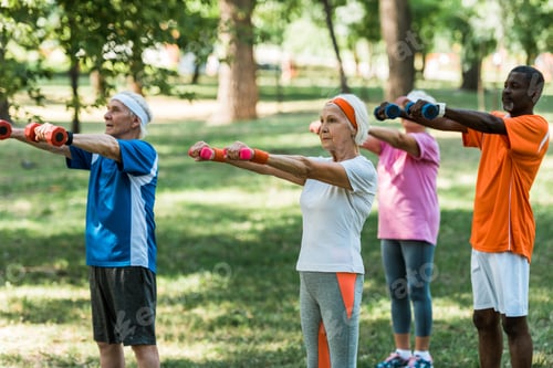 Preview: selective focus of pensioners in sportswear training with dumbbells in park