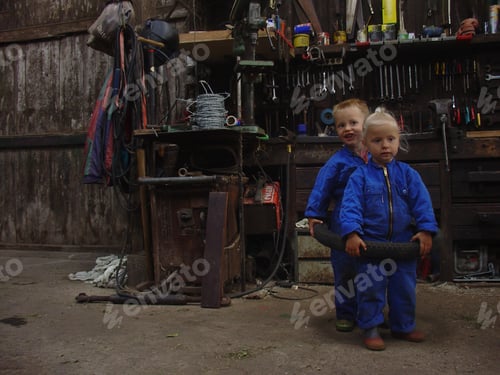 Preview: Kids being kids: little girl and boy playing in the work shed of their father.