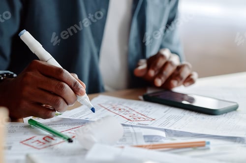 Preview: Young Black Man Reviewing Invoices and Bills with Smartphone at Desk