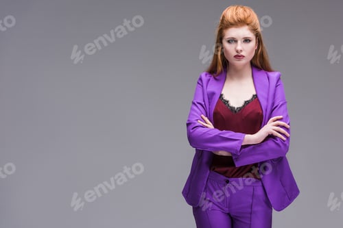 Preview: Young stylish female model dressed in purple suit isolated on grey