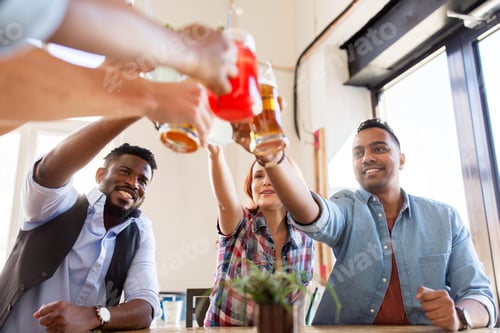Preview: friends clinking glasses with drinks at restaurant