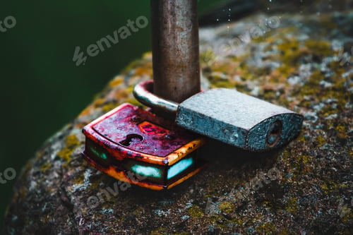 Preview: Wet old rusty locks firmly mounted on a wet stone in the rain.