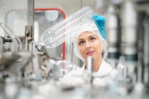 Preview: Female worker inspecting water bottle on production line in spring water factory