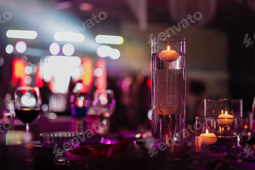 Preview: Banquet table decorated with burning candles in glass vases in restaurant hall. In the background