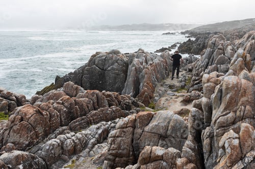 Preview: Man walking on the jagged rocks and the rocky coastline of the Atlantic ocean