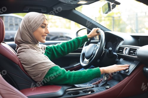Preview: Cheerful muslim woman driving car, turning on music