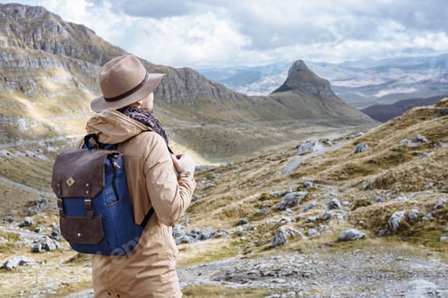 Preview: Young man in Hat with backpack starting an adventure in the mountain in Montenegro