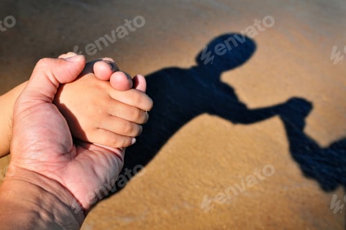 Preview: Closeup of an adult and children holding hands with their shadows in brown sand background.