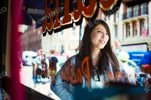 Preview: Young Japanese enjoying a day out in London, walking past a shop window.