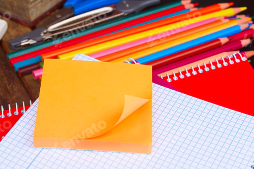 Preview: Empty notebook and set of colorful pencils on black board