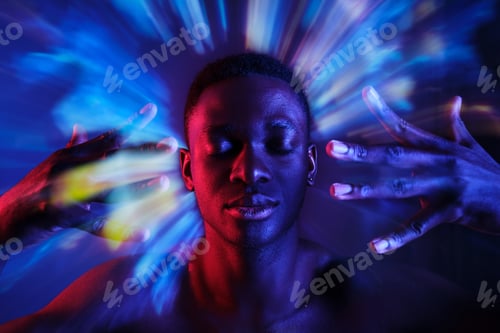 Preview: Shirtless black man holding hands near face in blurred lights
