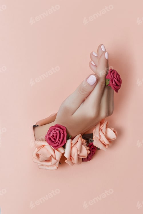 Preview: Hand with paper flowers and painted nails is thrust through a hole in the paper background
