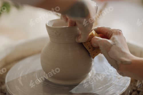 Preview: Close up of hands of professional potter molding pot shape on pottery wheel. Ceramics art concept