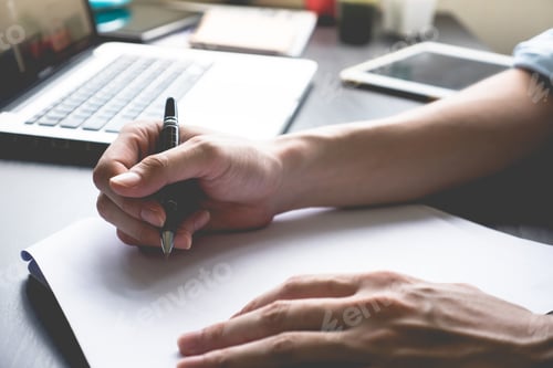 Preview: Close up of male hands writing on paper on his office desk.