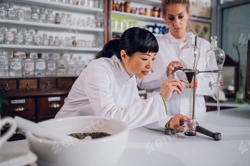 Preview: Multicultural chemists are using lab equipment for drug making in a pharmacy.