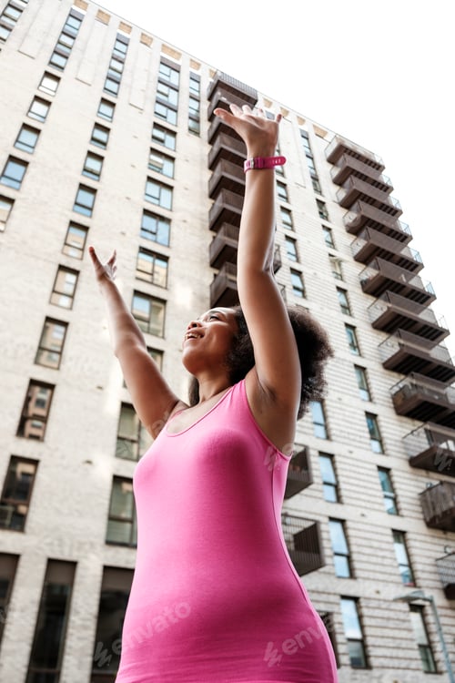 Preview: Young woman raising arms celebrating success in the city
