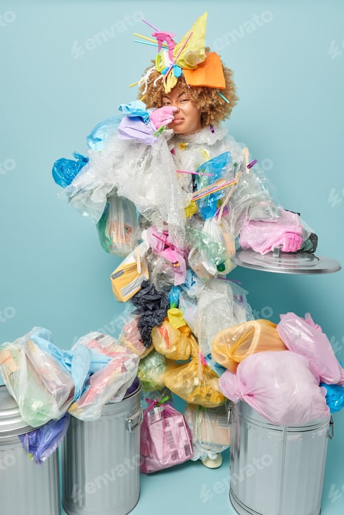 Preview: Displeased curly haired woman covers nose smells unpleasant odor from rubbish collects litter