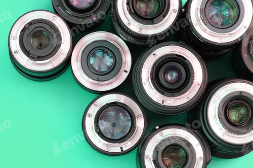 Preview: Several photographic lenses lie on a bright turquoise background. Copy space