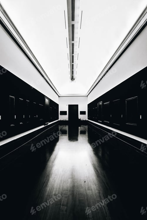 Preview: Vertical grayscale shot of an empty museum with empty frames on dark walls and illuminated ceiling