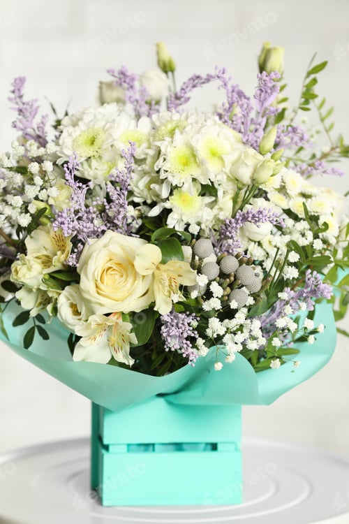 Preview: Beautiful bouquet of flowers in decorative crate on table against light background