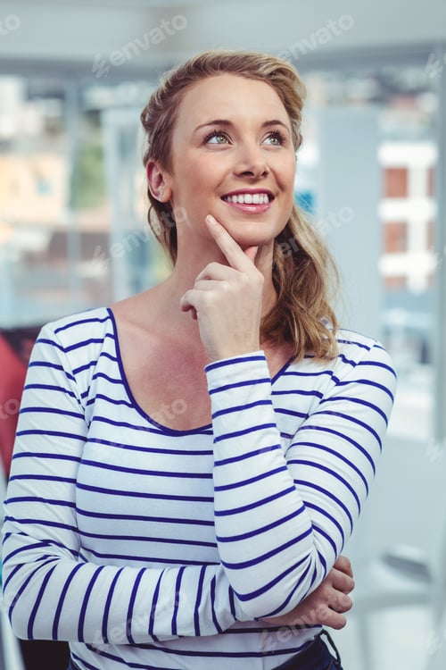 Preview: Smiling businesswoman in striped shirt thinking creatively in modern office