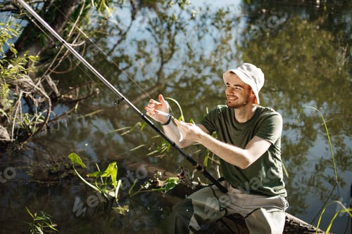 Preview: Young fisherman with fishing rod near the lake at summer