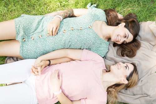 Preview: Young women holding hands while lying in the park
