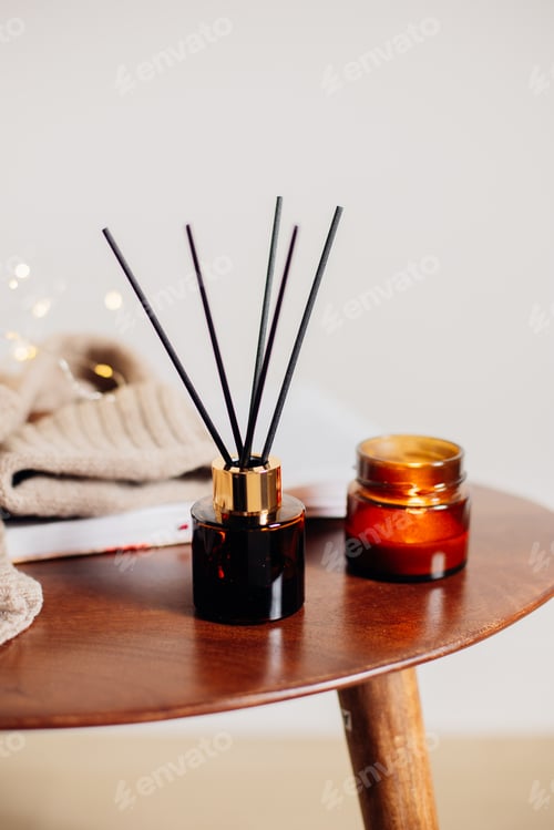 Preview: Home aroma fragrance diffuser and burning candles on wooden table in the bedroom. Interior element
