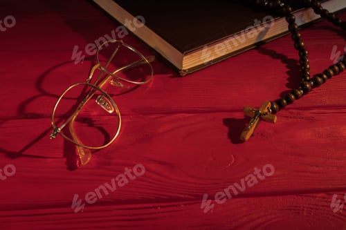 Preview: Rosary, Book and Glasses on Red Wooden Surface