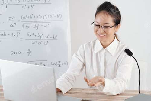Preview: Smiling young woman teaching remotely from home, whiteboard with math formulas in background