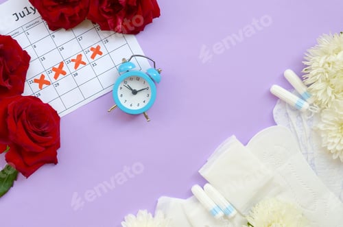 Preview: Menstrual pads and tampons on menstruation period calendar with blue alarm clock and red roses