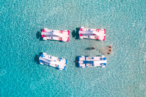 Preview: Aerial view of catamarans, swimming people in blue sea in summer