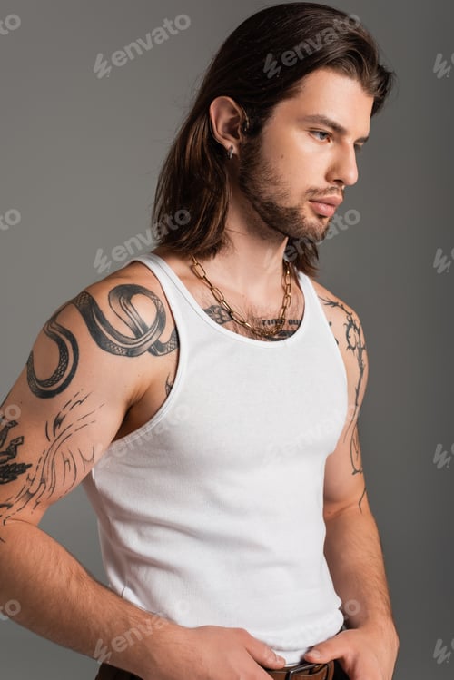 Preview: Long haired man with tattoo on body posing isolated on grey