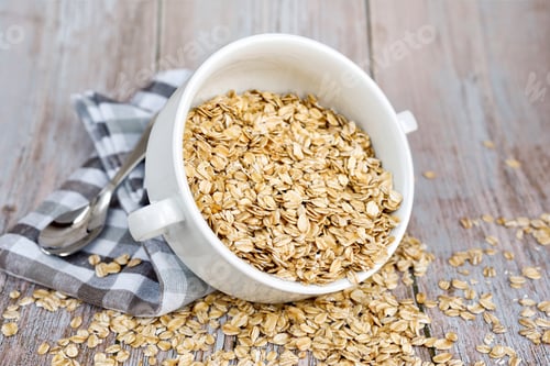 Preview: Oat flakes uncooked in a white bowl on rustic table. Healthy food for breakfast