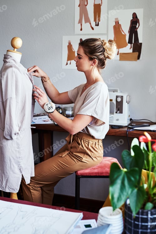 Preview: Shot of a young fashion designer working on a garment hanging over a mannequin
