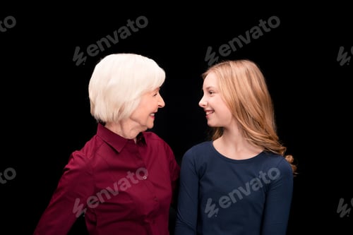 Preview: happy grandchild and grandmother looking at each other isolated on black