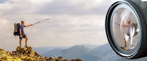 Preview: Man on peak of mountain in digital photo camera lens reflection.