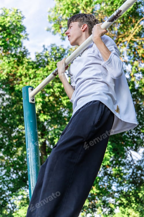 Preview: Young Man Doing Pull-Ups on a Bar in a Park on a Sunny Day