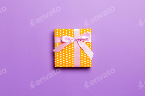 Preview: Top view Christmas present box with pink bow on purple background with copy space