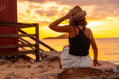 Preview: Woman with hat at sunset in Cala Comte beach on the island of Ibiza. Balearic