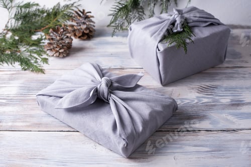 Preview: Two christmas gifts wrapped in gray linen cloth, zero waste concept.