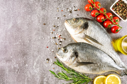 Preview: Seafood, fresh fish dorado and ingredients for cooking on gray background. Top view with copy space