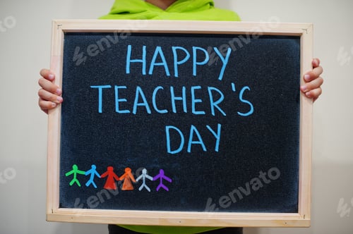 Visualização: Feliz dia do professor. Menino segura quadro-negro com inscrição azul
.