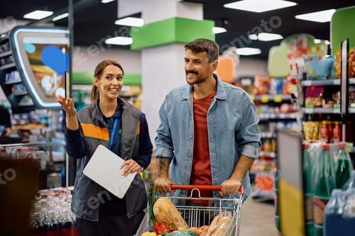 Preview: Happy man talking to female manager while buying in supermarket.