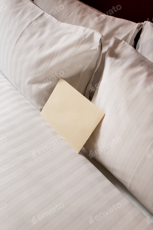 Preview: high angle view of blank envelope on white and clean bedding in hotel room