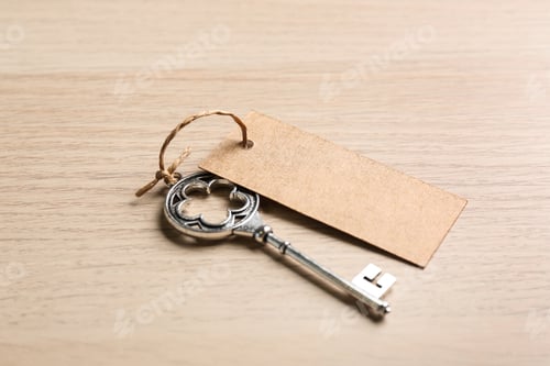Preview: Key with blank tag on wooden table. Keyword concept