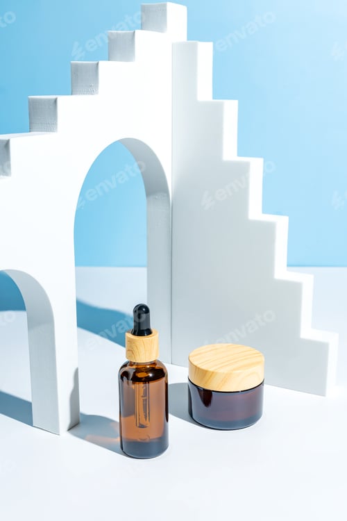 Preview: Moisturizer cream jar, serum in amber glass bottle on blue background. trendy podiums for cosmetics