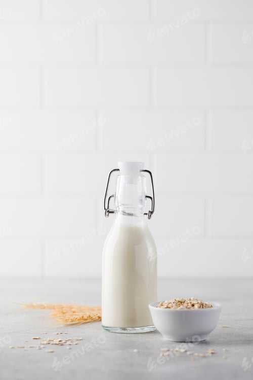 Preview: Alternative vegetable milk from oat flakes in a bottle on a light background. Vegetarian milk.