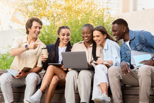 Preview: Multiracial group of students sitting on bench, using laptop
