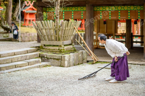 Preview: Nara, Japan - November 18, 2012: A Shinto Priest Rakes A Gravel Zen Garden At Kasuga-Taisha Shrine